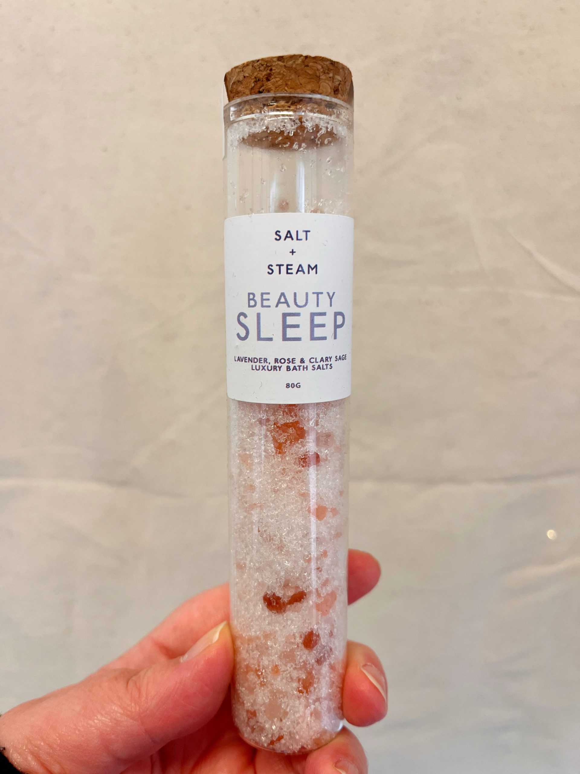 Beauty Sleep Bath Salts by Salt + Steam against a neutral background. The bath salts are in a clear glass test tube shaped container with a real cork lid.