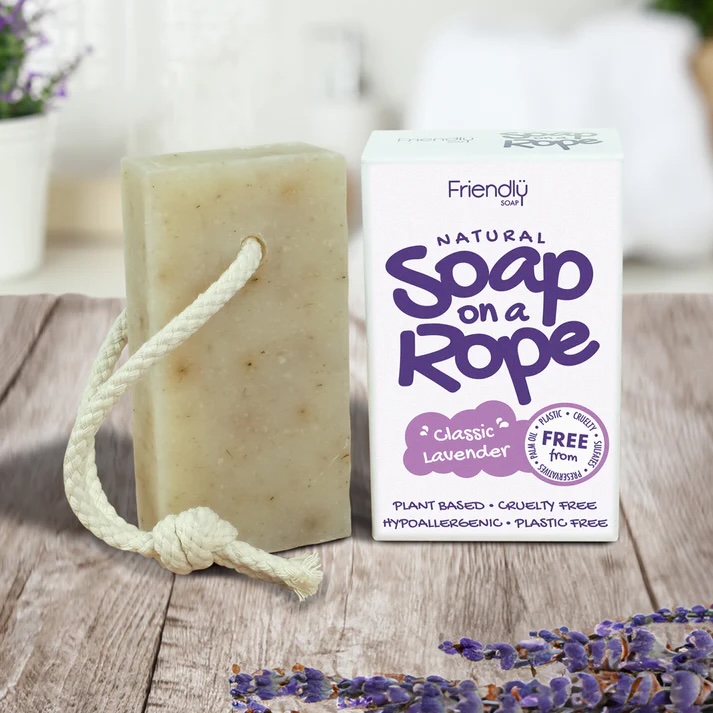 Friendly Soap Lavender natural Soap on a Rope. Pictured with a white piece of rope through the soap bar, standing next to its white box packaging with purple text