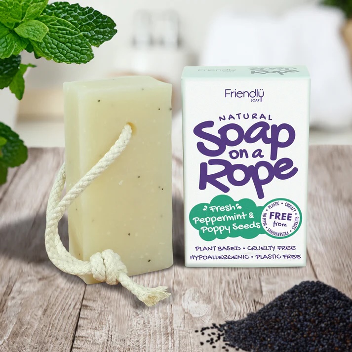 Friendly Soap Peppermint & Poppyseed natural Soap on a Rope. Pictured with a white piece of rope through the soap bar, standing next to its white box packaging with purple text